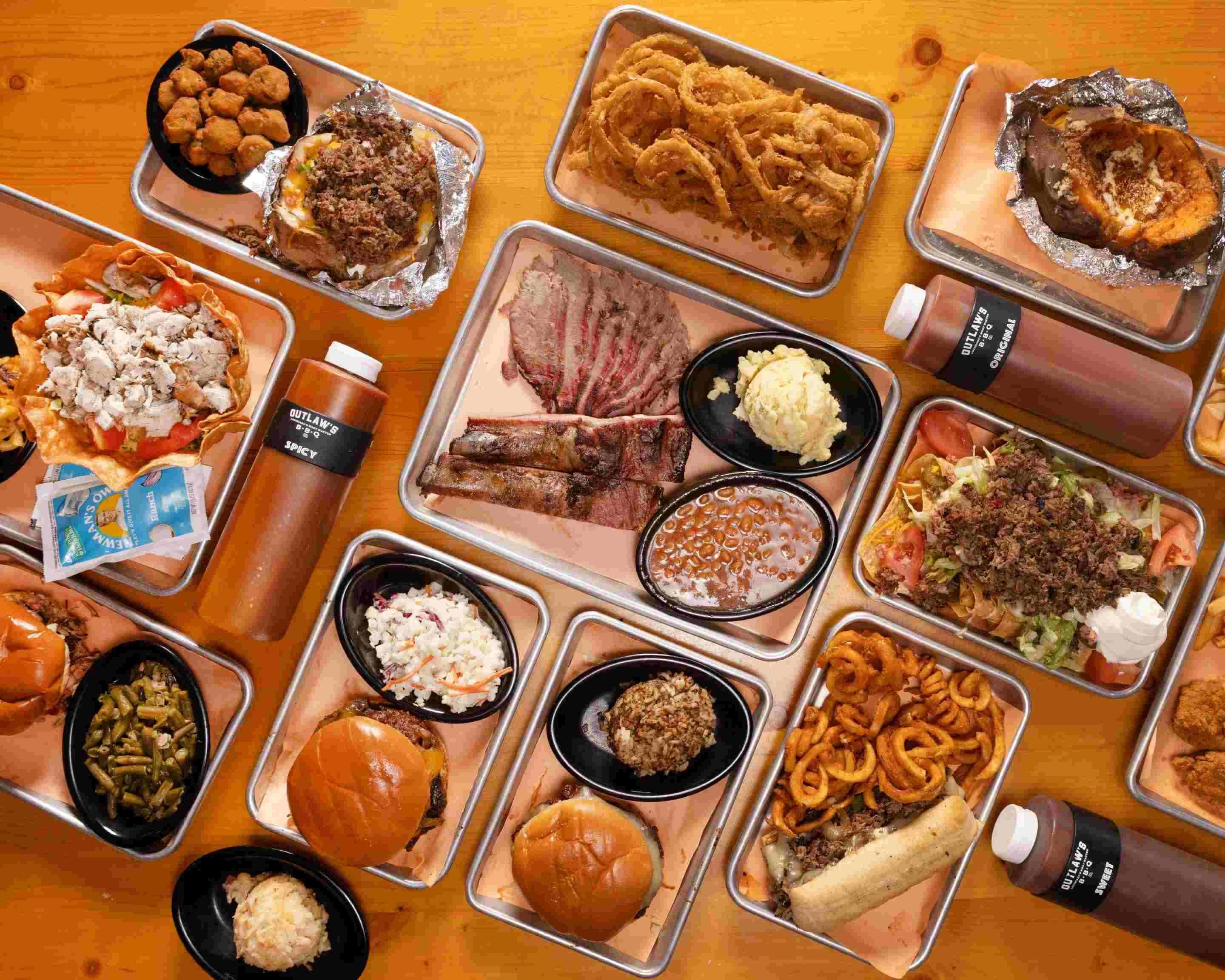 A variety of BBQ dishes including ribs, pulled pork, burgers, and sides like macaroni and cheese, onion rings, and coleslaw.
