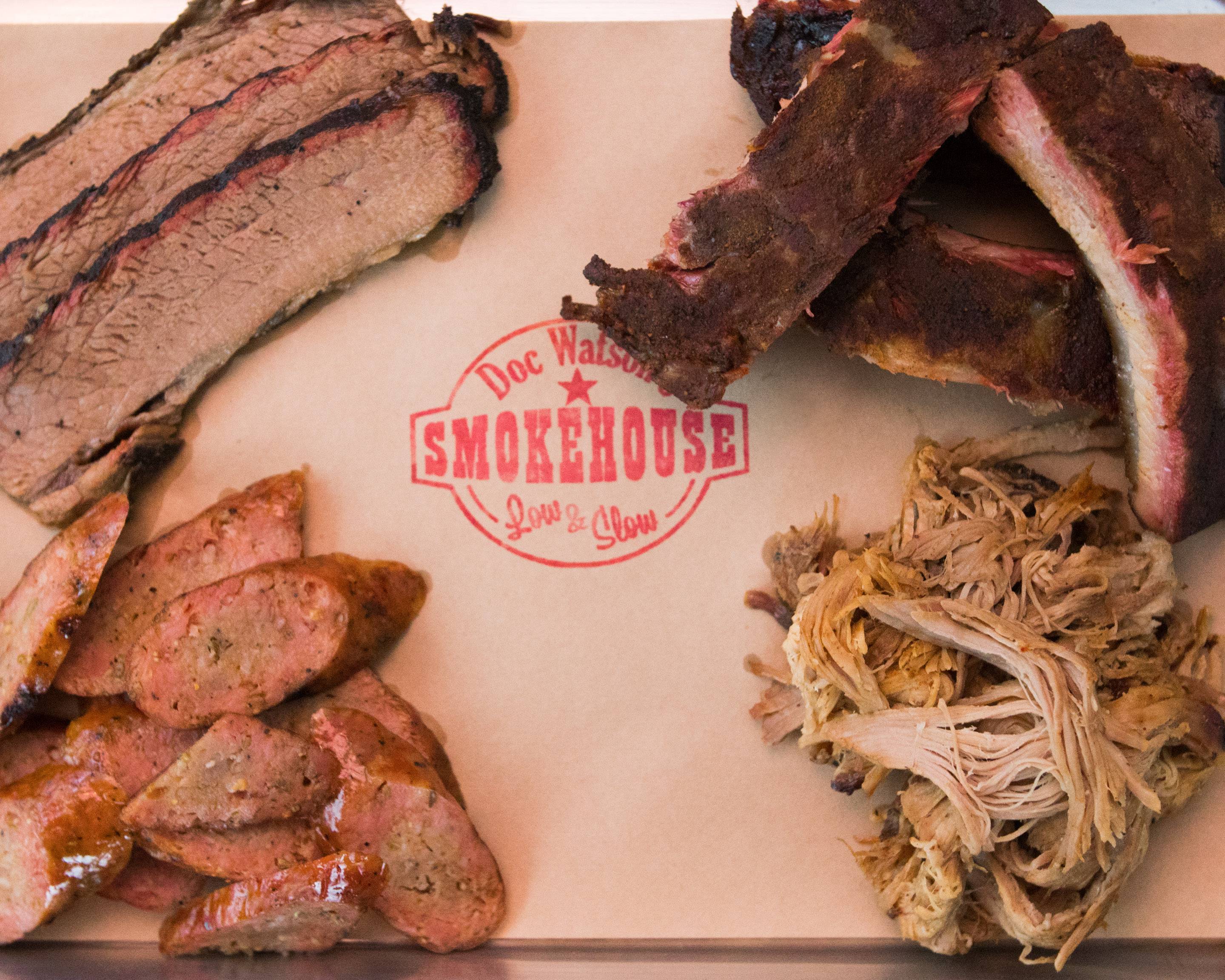 Assortment of BBQ meats including brisket, ribs, sausage, and pulled pork on butcher paper.