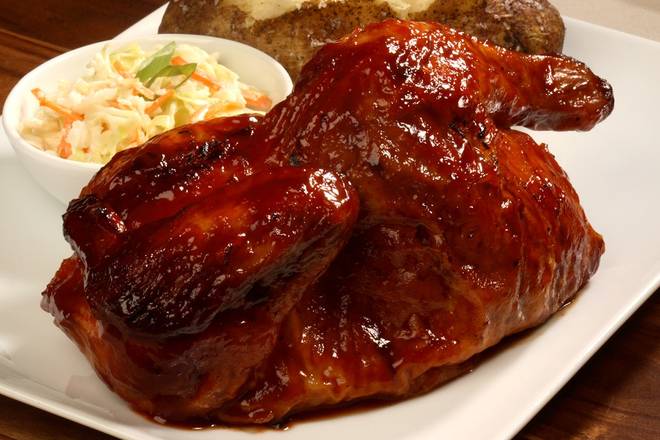 A chicken dish with a glossy BBQ glaze, served with coleslaw and a baked potato.