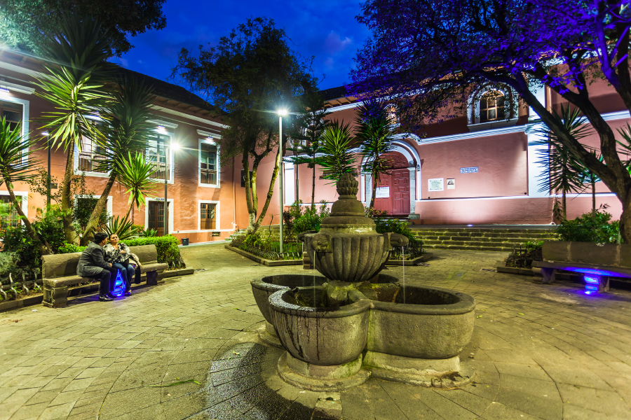 Plaza con una fuente en el centro al anochecer en el barrio San Marcos