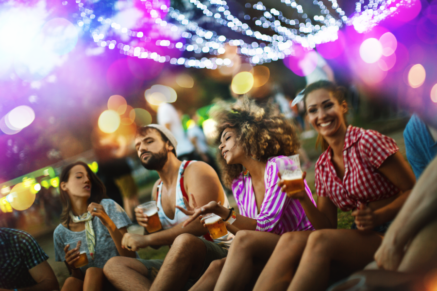 Grupo de amigos sentados en un parque tomando algo mientras escuchan música